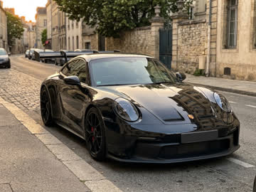 Black sports car parked on a cobbled street, used as an example upload