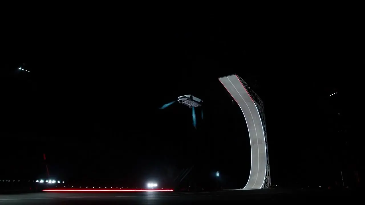 Frame from the Roadster ramp reference: the car turns upside down in the dark after leaving a tall curved ramp, with blue gas jets firing